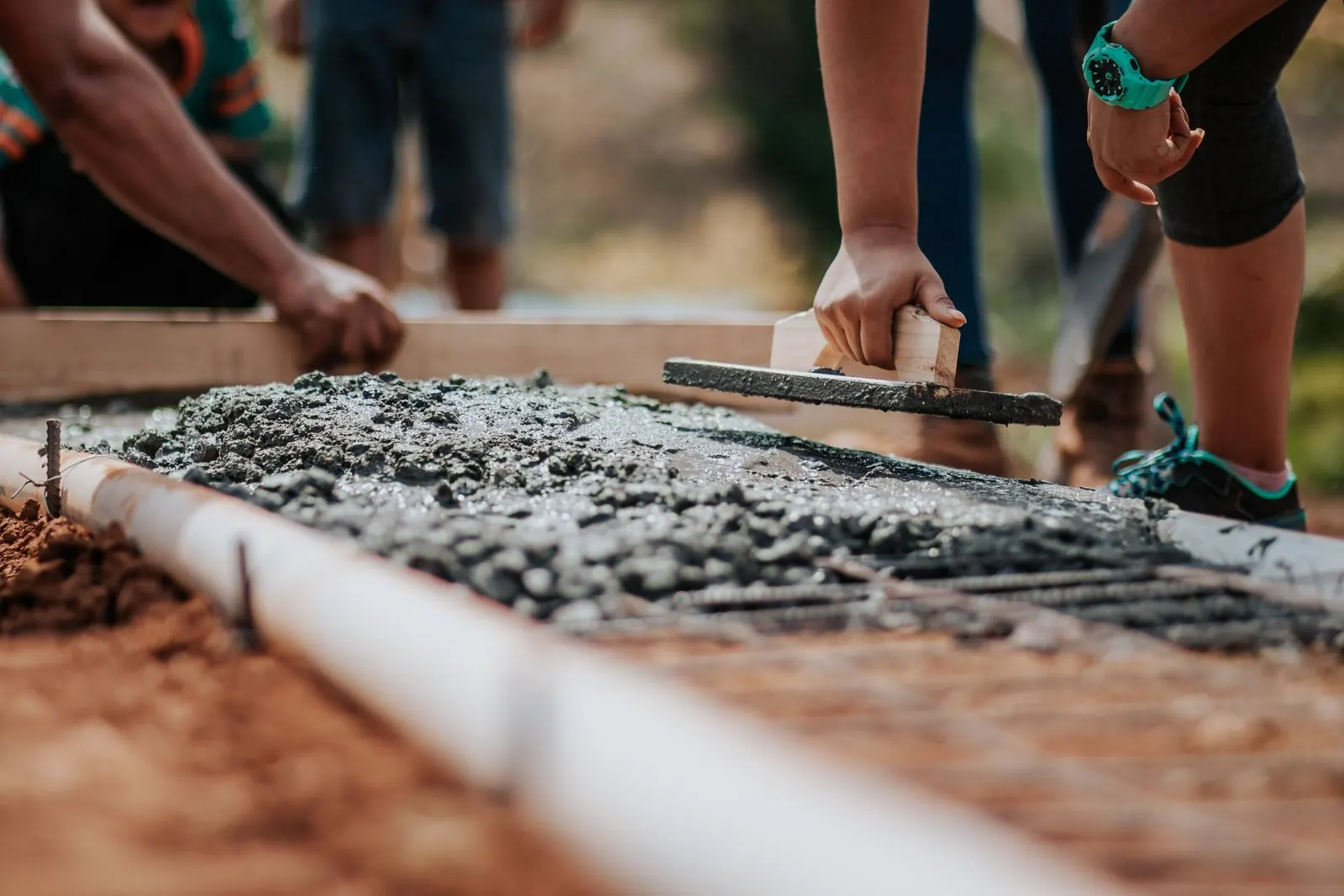 Concrete finisher smoothing the edge of a fresh slab with a hand float
