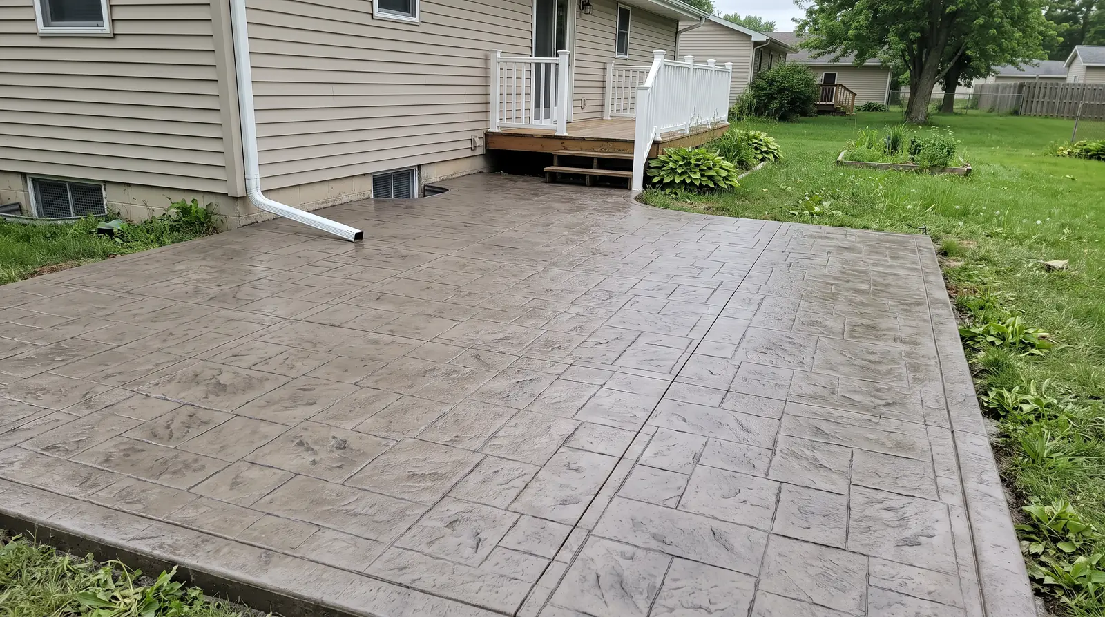 Stamped concrete patio in an ashlar slate pattern behind a home, poured as one continuous slab