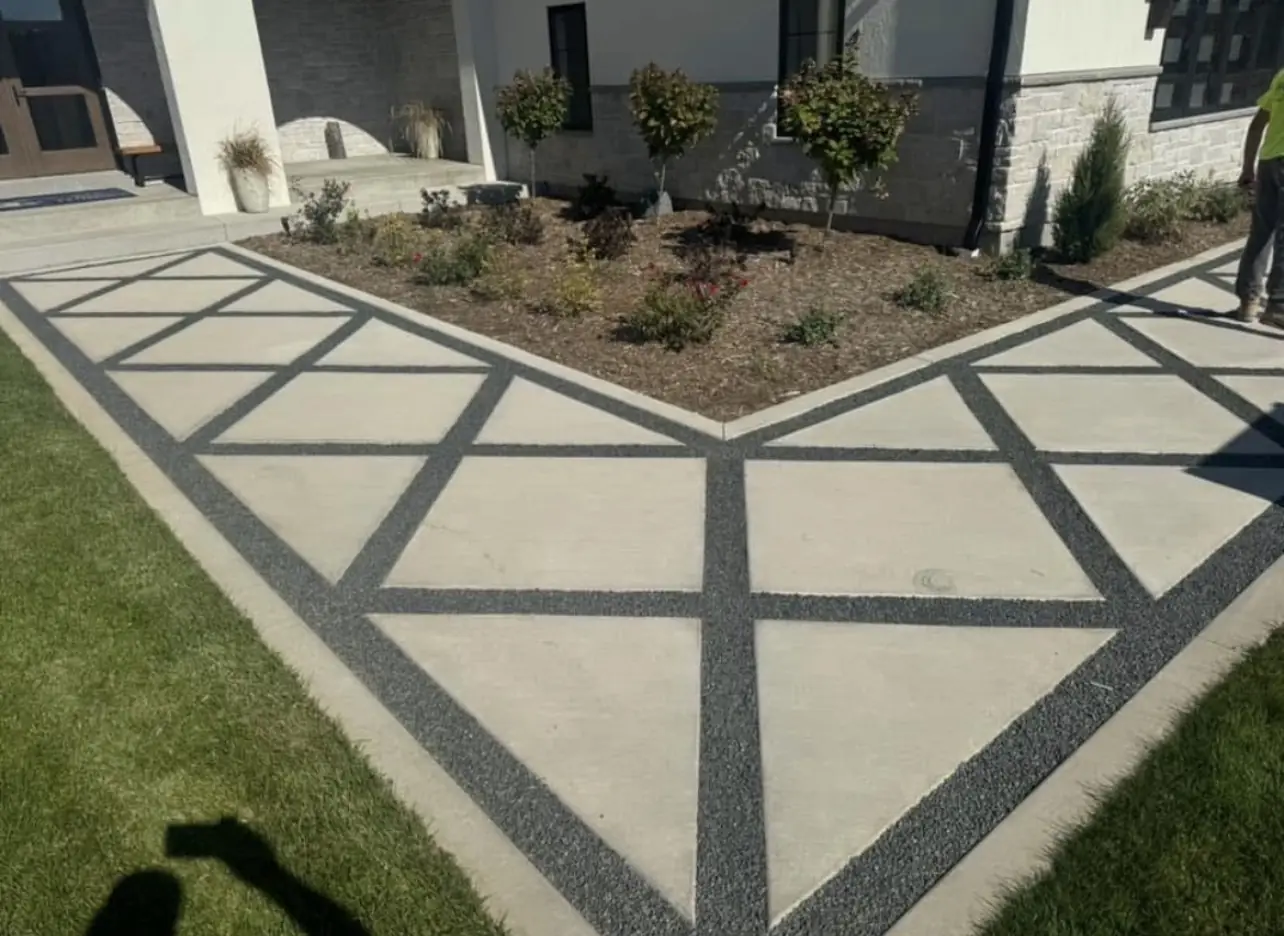 Smooth concrete walkway panels framed by exposed aggregate bands laid out in diamonds